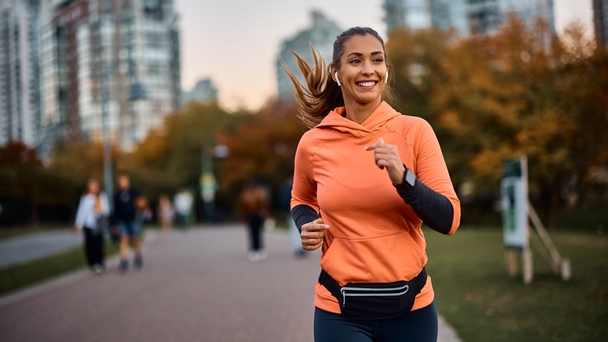 Mulher praticando corrida em parque urbano para artigo de saúde emocional