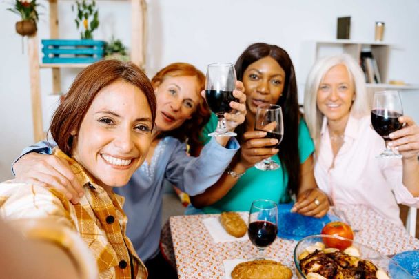 Mulheres de diferentes idades brindando em uma refeição social